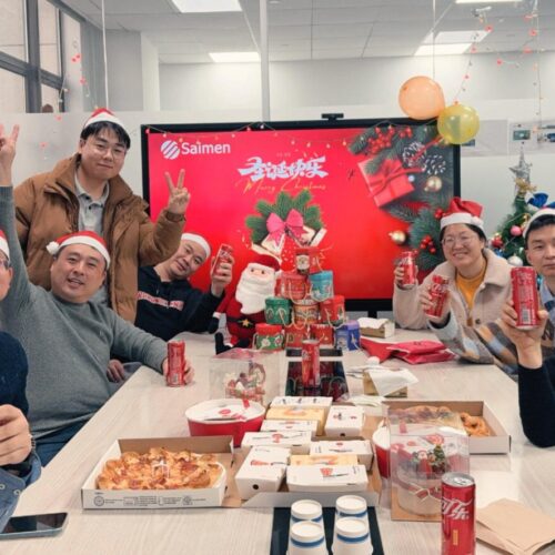 Gruppo di membri del team Saimen che si godono una festosa festa di Natale in ufficio con decorazioni e spuntini